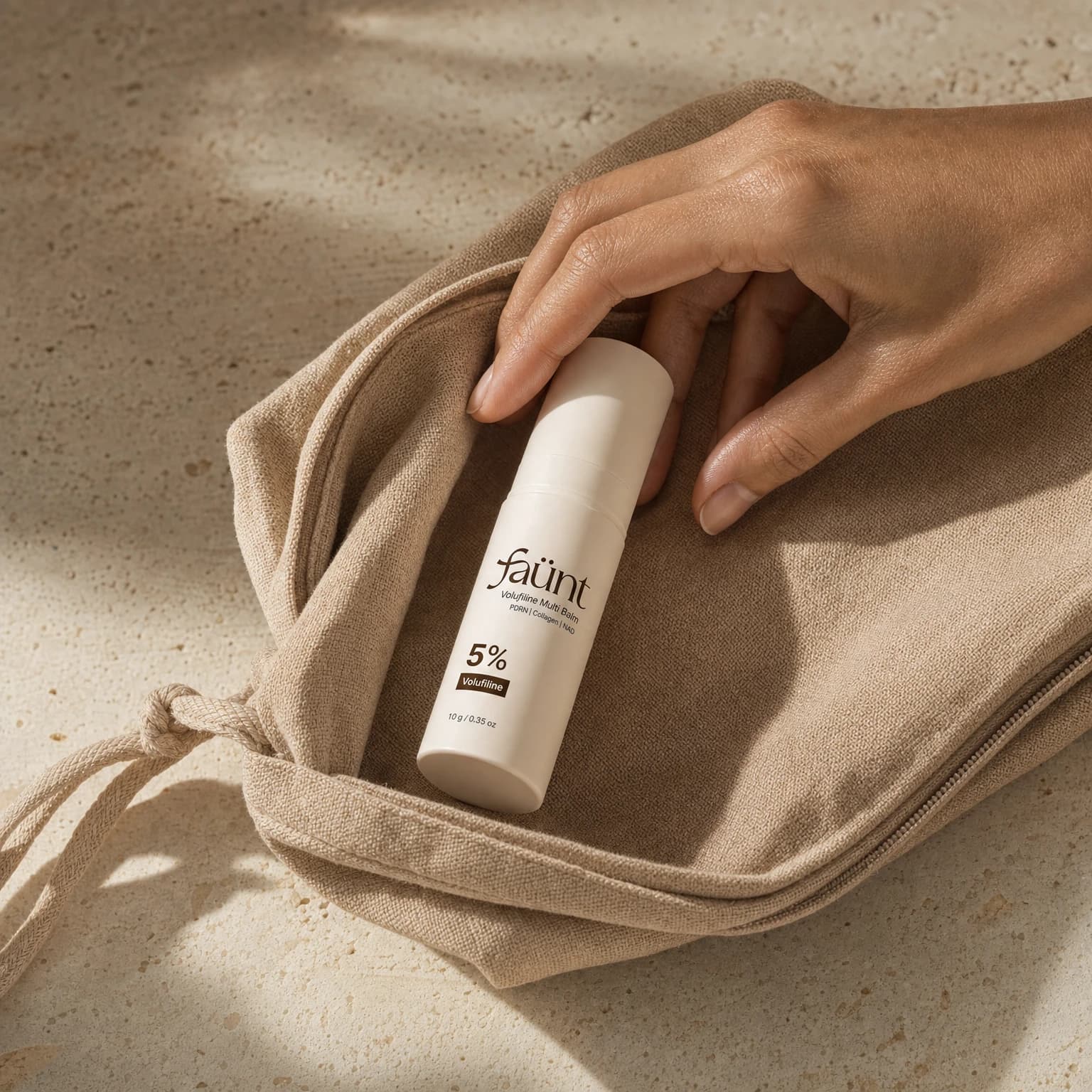 Capped Faünt multibalm beside an open toiletry pouch, ready to take along